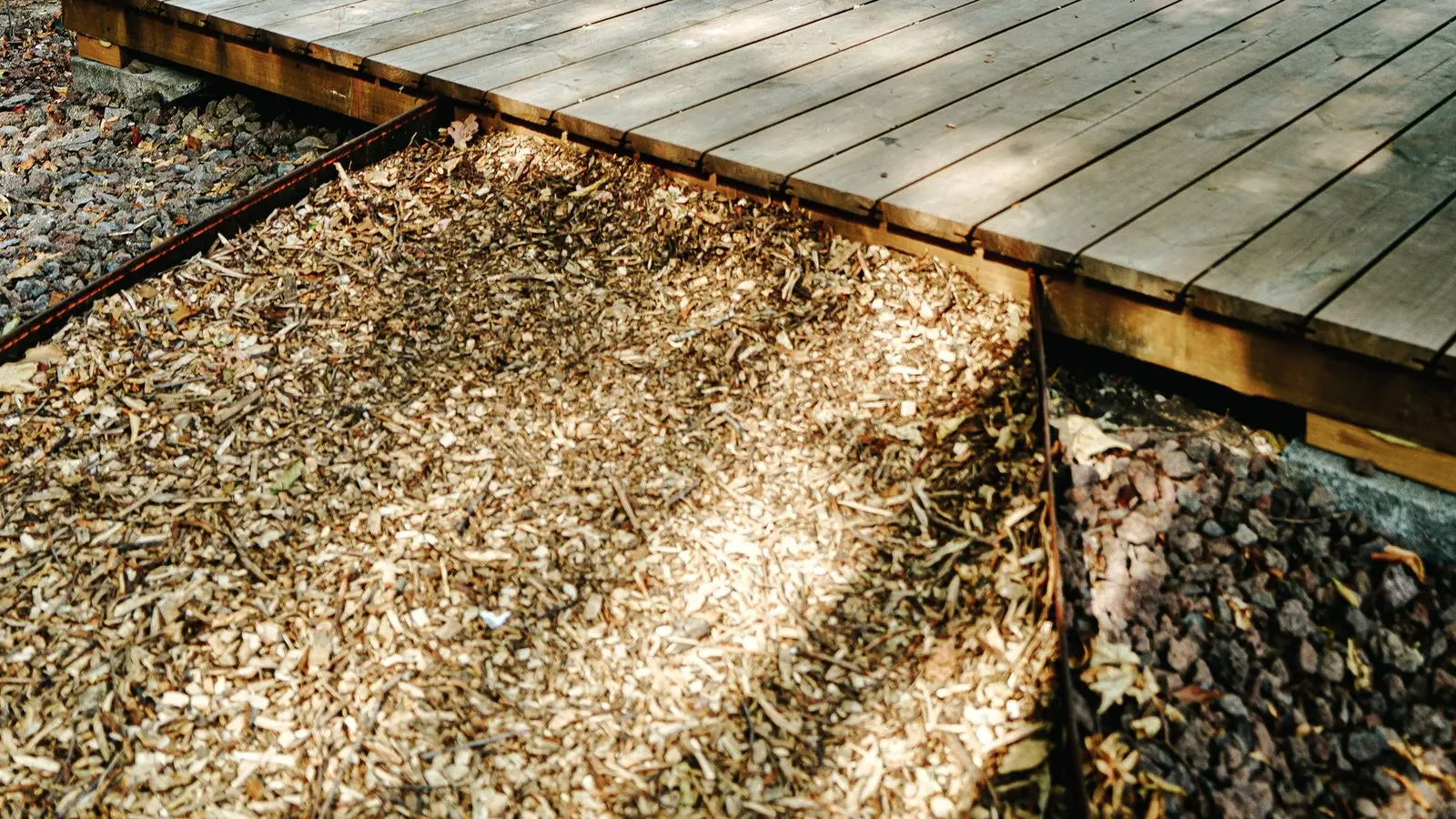 Low wood deck built beside a tall natural privacy fence